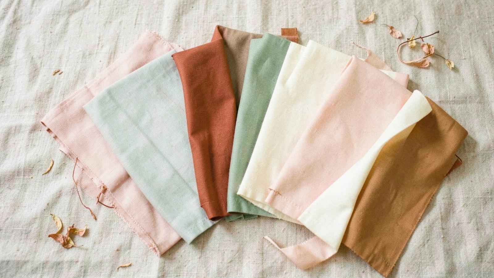Fabric swatches in blush, sage, terracotta and cream fanned out on a linen surface